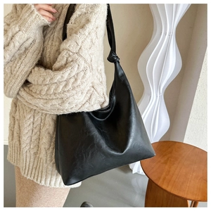 Detail of minimalist black PU leather hobo bag featuring a unique handcrafted knotted strap