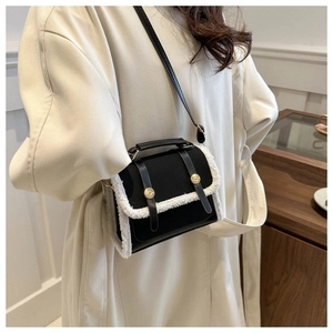 Detail of crossbody bag with white faux shearling trim and gold-toned metal buckles