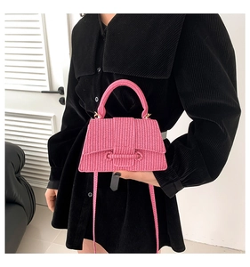 Detail of bright pink woven texture handbag with rounded handle shown by a model