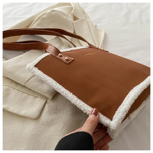 Close-up of caramel leather and white faux shearling tote bag with golden rivet details