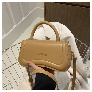 Close-up of caramel retro handbag with gold hardware and embossed fashion text in cart