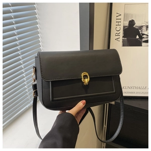 Vue détaillée du fermoir doré à nœud sur un sac à bandoulière en cuir noir mat