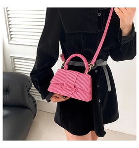Detail of pink woven crossbody bag featuring textured handle and gold metallic buckle