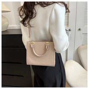 Detail view of stylish beige square crossbody bag with stitching and gold-tone hardware