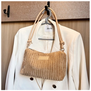 Detail of beige corduroy shoulder bag showing vertical ribbed texture and slim straps