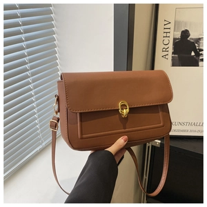 Vue détaillée du sac bandoulière marron avec boucle dorée sur fond urbain moderne