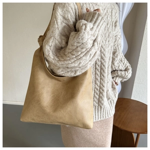 Detail of camel brown vintage faux leather shoulder bag with knotted strap and wrinkled texture