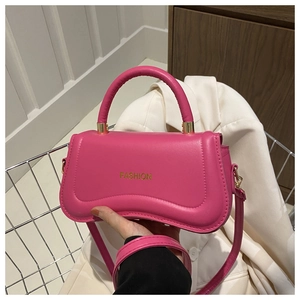Detail of rose pink leather handbag featuring curved base and FASHION lettering