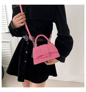 Close-up of pink woven texture handbag with crossbody strap on black velvet dress