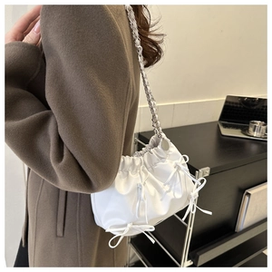 Detailed view of white cloud-shaped shoulder bag with decorative bows and silver chain strap