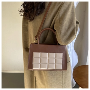 Brown and beige square quilted tote bag styled with a warm coat in a modern interior
