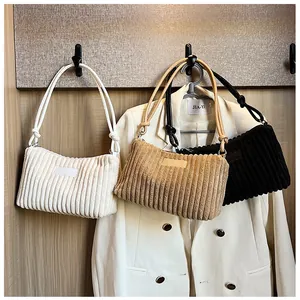 Detail view of corduroy shoulder bags in white, beige and black with knot strap design