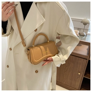 Detail of camel PU leather handbag featuring FASHION text and gold metal strap hardware