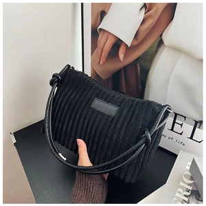 Close-up of black corduroy hobo bag showing soft ribbed texture and minimalist label piece