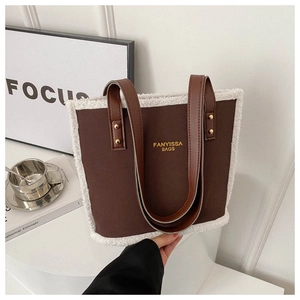 Detail of a brown leather shoulder bag with white faux fur trim and gold rivet accents