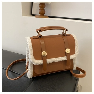 Close-up of brown PU leather handbag with white faux shearling trim and gold buttons