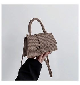 Detailed view of khaki woven handbag showing fine synthetic leather texture and handle
