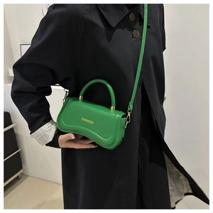Detail view of a vibrant green PU leather handbag featuring golden FASHION text and stitching