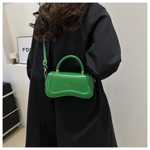 Detail of bright green PU leather handbag with gold logo and unique wavy bottom curve