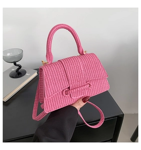 Detail of pink woven texture on trapezoid handbag with gold metallic buckle closure