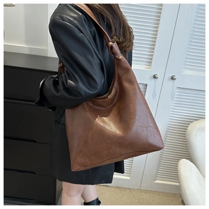 Detail of dark brown faux leather tote bag with unique knotted wide shoulder strap design