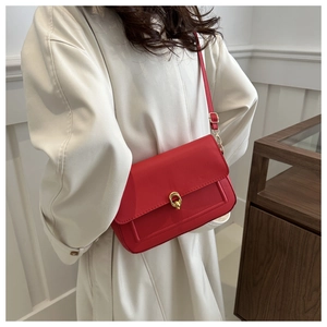 Sac bandoulière rouge en cuir avec boucle dorée assorti à un long manteau blanc