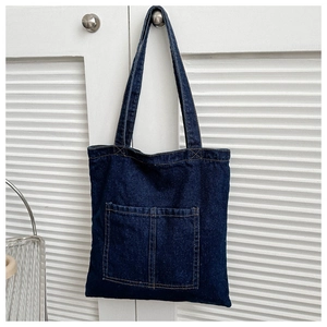 Close-up of deep blue denim tote bag with two front pockets and yellow stitching details