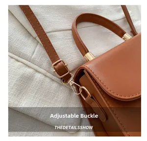Detail of adjustable golden metal buckle on a brown leather crossbody shoulder bag