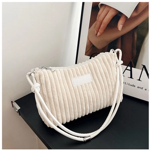 Cream corduroy shoulder bag with vertical stripe texture and slim strap on desk