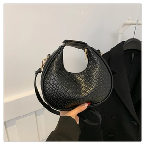 Close-up of black woven texture on a crescent handbag with premium gold zipper and strap