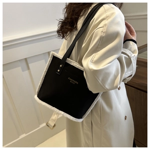 Detail of black leather shoulder bag featuring white faux fur trim and gold lettering