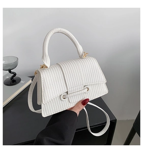 Close-up of white woven leather crossbody bag with golden hardware and top handle