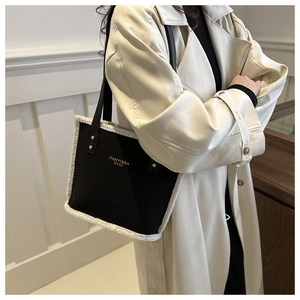 Fashionable black leather tote bag with white faux fur trim shown on a model