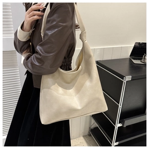 Detail of minimalist cream leather bucket bag with a stylish knotted shoulder strap design