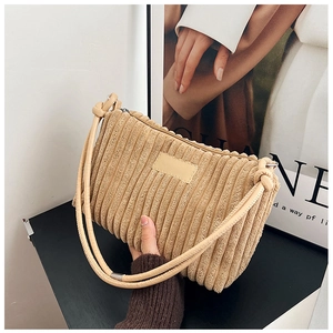 Close-up of beige corduroy shoulder bag showing ribbed texture and zipper detail