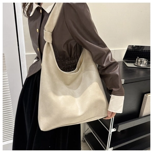 Detail of minimalist cream PU leather hobo bag with knotted strap on a model's shoulder