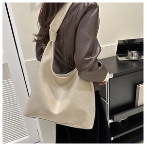 Detail of soft cream leather tote bag with unique knotted strap shown on model shoulder