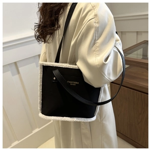Detail of square black shoulder bag with white faux shearling trim and gold brand logo