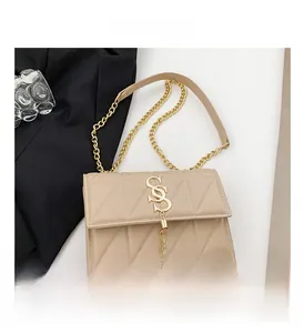 Detail of beige quilted crossbody bag with gold S-logo buckle and fringe tassel accessory