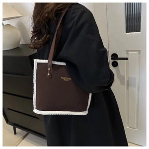 Brown leather tote bag with white fleece trim and gold lettering shown in a home setting