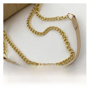 Detail of light brown leather shoulder strap with polished gold metal chain stitching