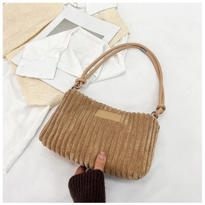 Close-up of vintage corduroy texture and decorative knotted shoulder straps on dark camel bag