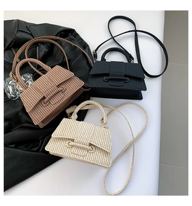 Detail of woven square bags in brown, black, and cream with metallic bar closure