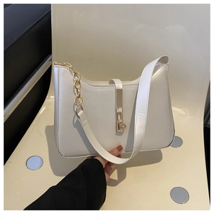 Detail view of cream leather shoulder bag with gold metal buckle and decorative chain