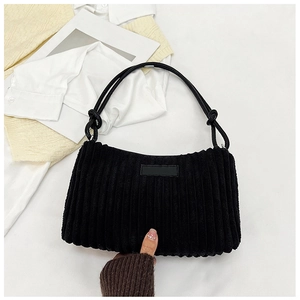 Detail of black corduroy shoulder bag showing fabric texture and decorative knot handle