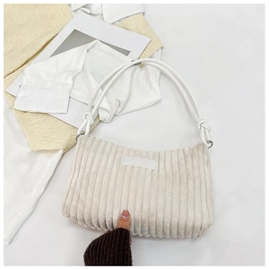 Close-up of cream corduroy shoulder bag showing wide ribbed texture and shoulder strap