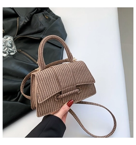 Detail of tan woven texture bag featuring elegant gold hardware and top handle strap