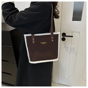 Detail of a brown leather tote bag with white plush trim worn by a model in a modern room