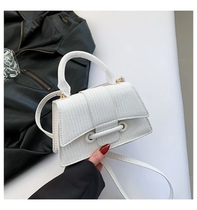 Detail of white woven texture handbag with gold hardware and adjustable strap