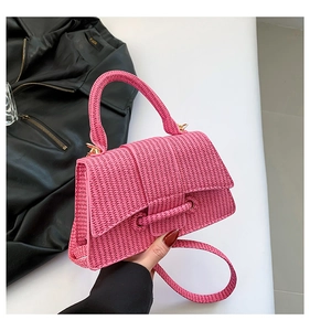 Detail of pink woven handbag featuring gold metal hardware and textured knit pattern